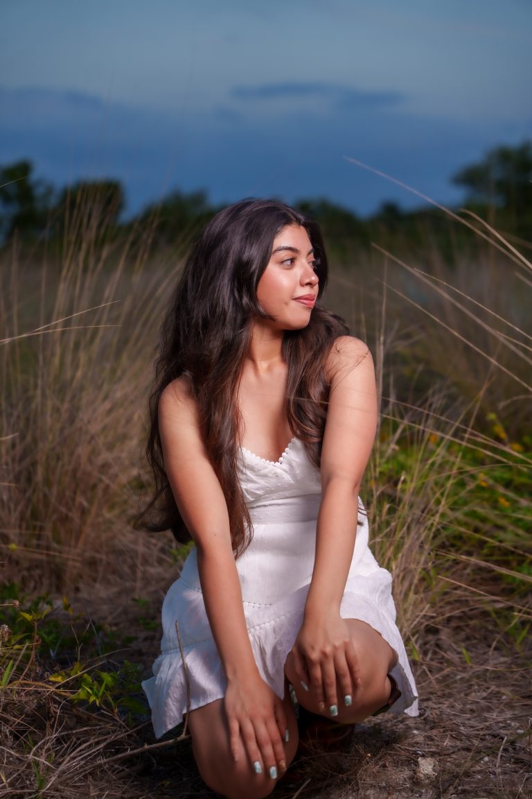 Portrait of a young woman in a field at dusk