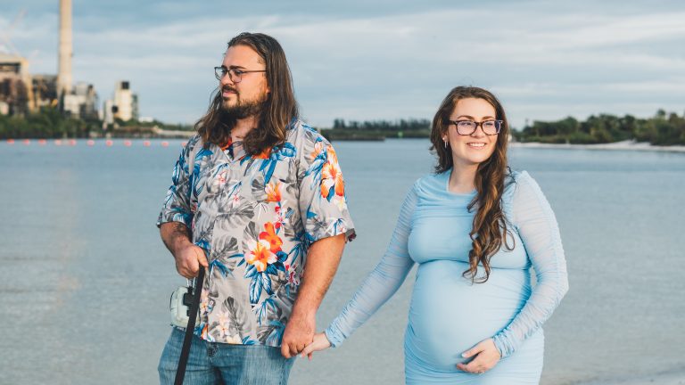 Maternity couple portrait by the water at sunset