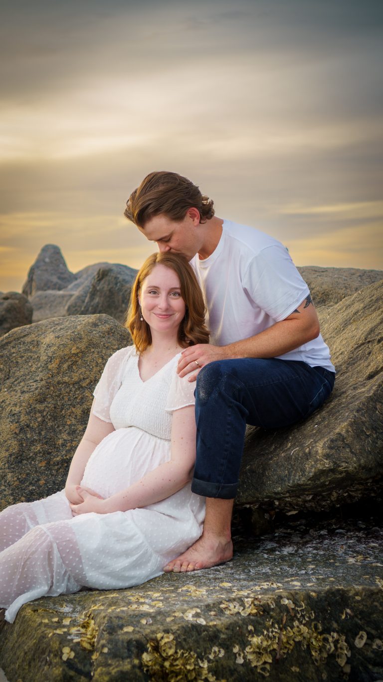 Maternity portrait of a couple on the rocks at golden hour in Apollo Beach